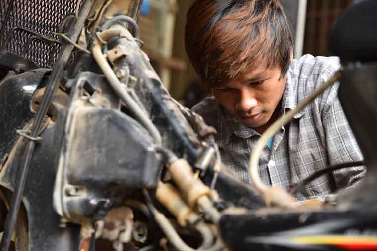バイク修理の職業訓練に取り組む少年の写真