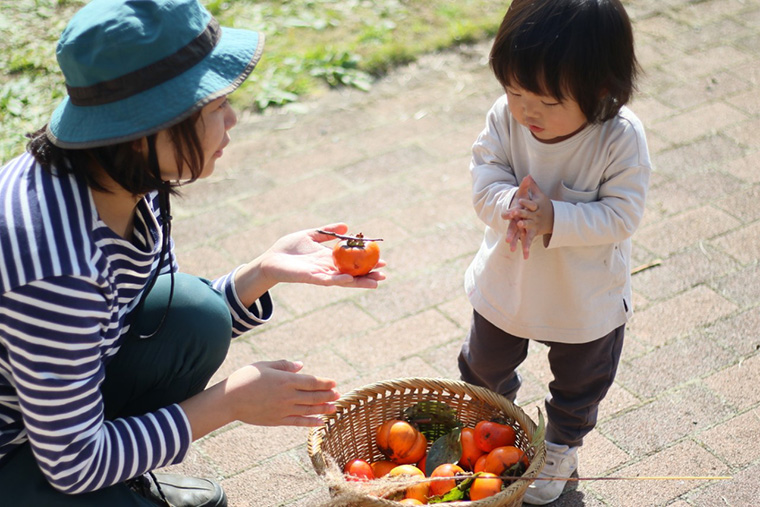 大人が柿を持って、その柿を子どもに見せている様子の写真